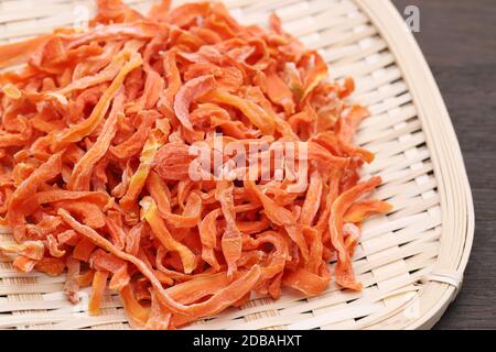 Carote tagliate essiccate in un cesto di bambù su tavola Foto Stock