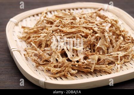 medicina cinese, piante secche in un cesto di bambù su una tavola di legno. Foto Stock