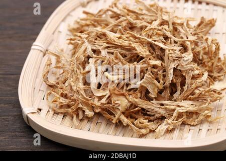 medicina cinese, piante secche in un cesto di bambù su una tavola di legno. Foto Stock