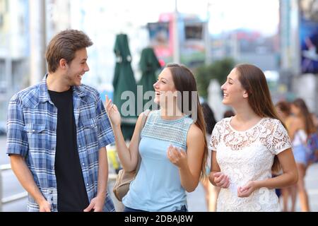 Buon gruppo di tre amici che ridono e parlano per strada Foto Stock