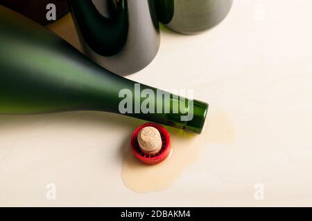 vista dall'alto della bottiglia di cognac rovesciata in liquido versato vicino a bottiglie di vino vuote su tavola di legno Foto Stock