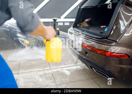 Gli specialisti applicano la pellicola di protezione dell'auto sul paraurti posteriore. Installazione di un rivestimento che protegge la vernice dell'automobile dai graffi. Veicolo nuovo in g Foto Stock