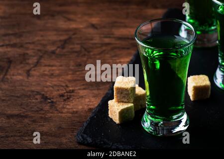Assenzio - bevanda alcolica forte, tintura di wormwood amaro verde in bicchieri sul vecchio tavolo di legno, posto per il testo Foto Stock