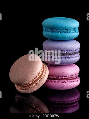 Tre macaroon l'uno l'altro e uno successivo su sfondo nero Foto Stock