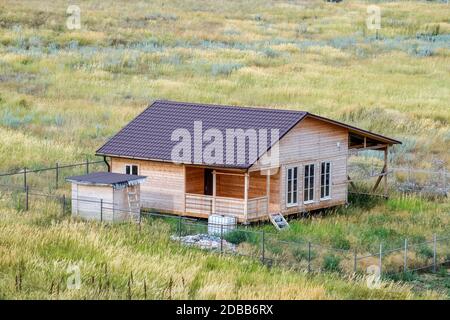 Una casa in legno di legno e tavole con un tetto in metallo. Casa tra le steppe. Foto Stock