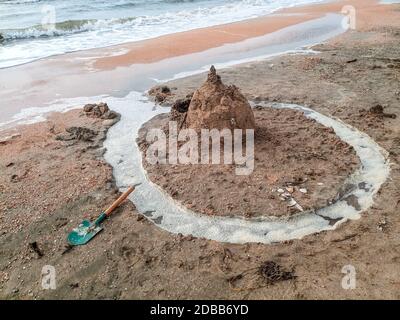 Castello di sabbia sulla spiaggia con conchiglie. Giochi per bambini in mare. Foto Stock