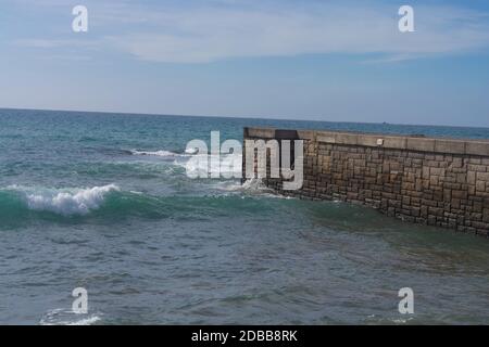 Onde alte a un frangiflutti su Cran Canaria a Meloneras, spiaggia vicino al faro. Foto Stock