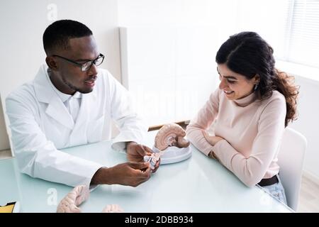 Medico che spiega i dettagli del cervello umano per donna felice con il modello Foto Stock