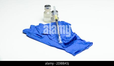 Una siringa vuota si trova sopra un paio di guanti e fiale mediche. Foto Stock