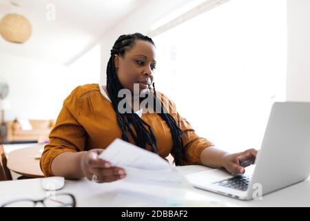 Donna che lavorano alla scrivania in ufficio in casa Foto Stock