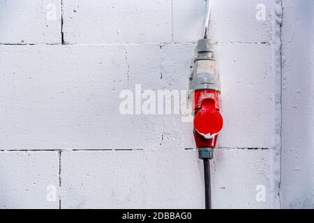 collegamento elettrico trifase alla parete bianca dai blocchi da costruzione, sfondo. Foto Stock