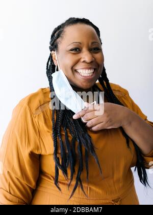 Studio ritratto di donna sorridente che regge maschera facciale protettiva Foto Stock