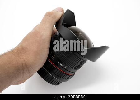 La mano tiene la lente fisheye nera su sfondo bianco Foto Stock