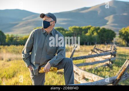 USA, Idaho, Bellevue, Farmer in maschera di fronte che pende contro recinzione sul campo Foto Stock