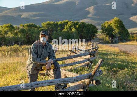 USA, Idaho, Bellevue, Farmer in maschera di fronte che pende contro recinzione sul campo Foto Stock