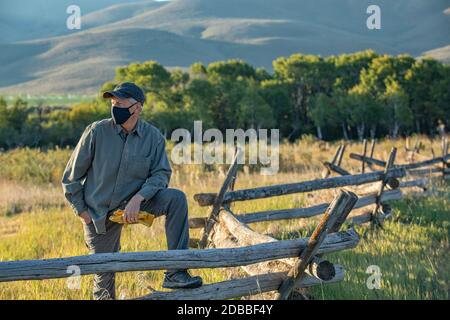 USA, Idaho, Bellevue, Farmer in maschera di fronte che pende contro recinzione sul campo Foto Stock