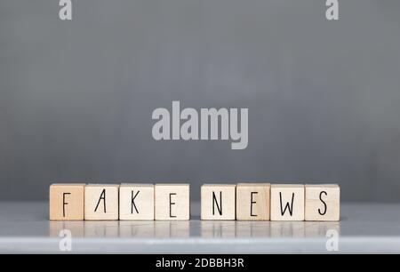 Cubess di legno con le parole Fake News su sfondo grigio, Fake News concetto di social media primo piano Foto Stock