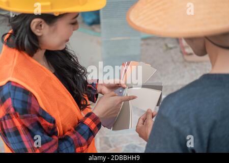 Primo piano del costruttore femminile che mostra un esempio di vernice sui costruttori in costruzione di edifici Foto Stock