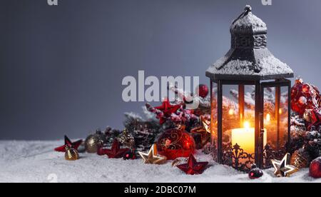 Composizione di Natale della lanterna ornamenti colorati sfere stelle candele e Abete rami sulla neve Foto Stock