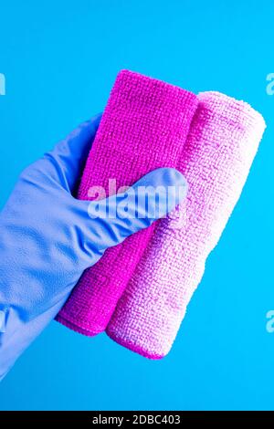 Mano femminile in gomma blu GHand in gomma guanti di protezione che reggono il panno. Detergente per diverse superfici in cucina, bagno e altre stanze. Clos Foto Stock