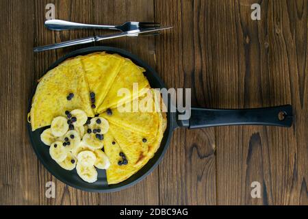 Gustosi pancake con banane e mirtilli su padella nera. Vista in primo piano. Frittelle fatte in casa. Pancakes colazione cibo. Foto Stock