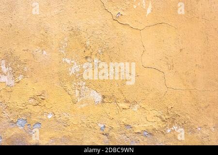 Grunge parete intonaco con sfondo giallo graffiato. Vecchio muro con buccia color palude stucco texture. Carta da parati vintage. Decadimento e crepe. Abstra ruvida Foto Stock