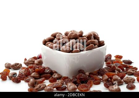 Snack malsani e dolci a base di cacao concetto di cioccolato lucido liscio uvetta ricoperta in recipiente di ceramica isolato su fondo bianco Foto Stock