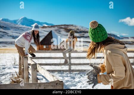 Tre giovani amiche felici si divertono a recinzione di legno in inverno all'aperto in montagna. Concetto di vacanza invernale Foto Stock