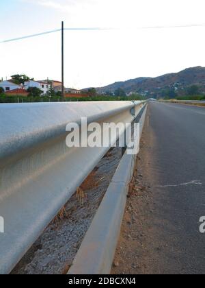 Un guardrail in acciaio su una strada rurale con una bella prospettiva. Foto Stock