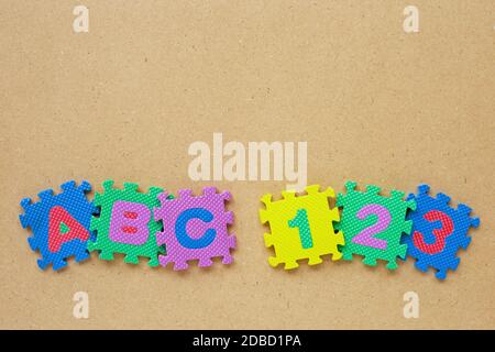 Alfabeto puzzle con numero puzzle su sfondo di legno. Vista superiore Foto Stock