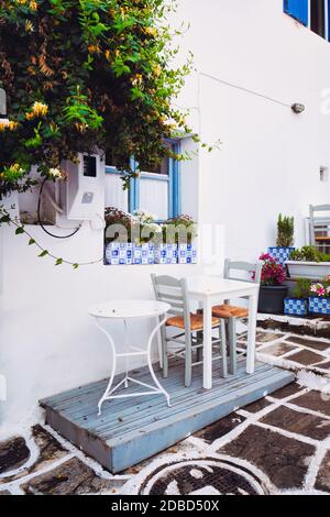 Pittoresca strada stretta con tradizionali case bianche con tavoli da caffe' della citta' di Naousa nella famosa attrazione turistica dell'isola di Paros, Grecia Foto Stock
