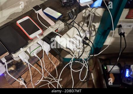 Molti caricabatterie per dispositivi aggrovigliati in un angolo affollato Foto Stock