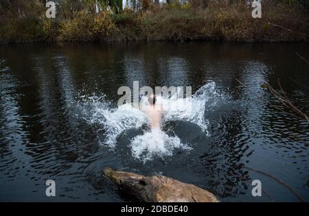 Laatzen, Germania. 17 Nov 2020. Un uomo salta nell'acqua fredda del fiume Leine nella regione di Hannover al mattino a una temperatura esterna di quasi 13 gradi. Nuotando in acqua fredda, l'uomo vuole rafforzare il suo sistema immunitario e le sue difese. Credit: Julian Stratenschulte/dpa/Alamy Live News Foto Stock