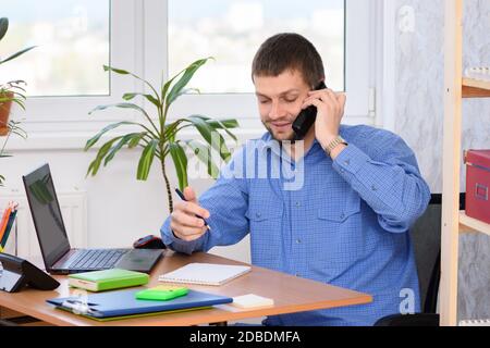 Specialista di ufficio che parla al telefono e prende appunti in un notebook Foto Stock