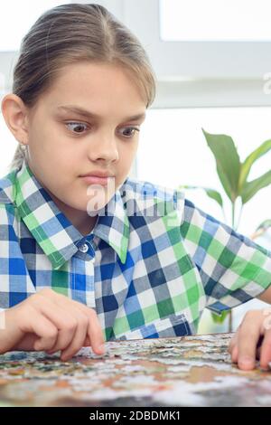 Ragazza a sorpresa guarda il puzzle sul tavolo Foto Stock