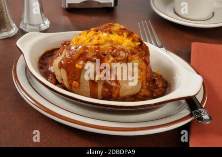 Una patata al forno condita con peperoncino con carne e cheddar formaggio Foto Stock