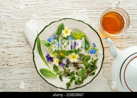 Tazza da tè di foglie di erbe fresche su sfondo di legno bianco, vista dall'alto, posto per il testo. Concetto sano Foto Stock