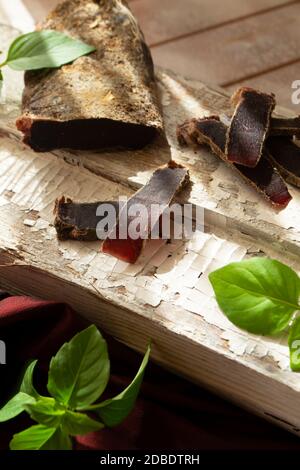 carne a stropiano, carne secca di cervo selvatico su un tavolo rustico, immagine verticale Foto Stock