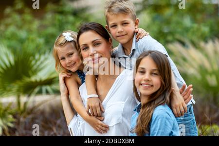 Ritratto di una bella giovane madre con piacere passare il tempo con i suoi tre bambini preziosi nel parco primaverile, divertirsi insieme, grande famiglia felice enj Foto Stock