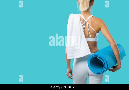 Bella donna sportiva che posa e tiene un tappetino per esercizi, fitness e workout concetto Foto Stock