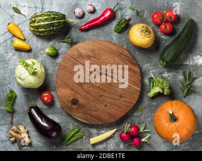 Selezione di verdure con vassoio rotondo in legno al centro con spazio di copia per testo o disegno. Zucchine, zucca, pomodori, cavoli, peperoni, rafano ed erbe vista dall'alto o piatto Foto Stock