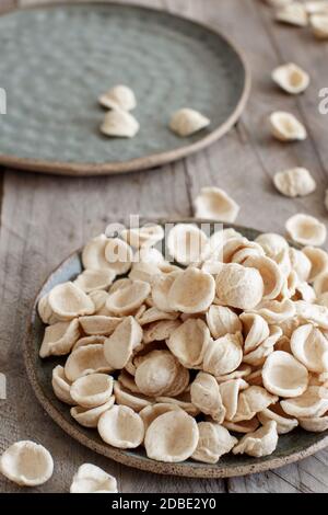 Orecchiette di pasta pugliese cruda e fresca a base di farina integrale su un tavolo di legno da primo piano Foto Stock