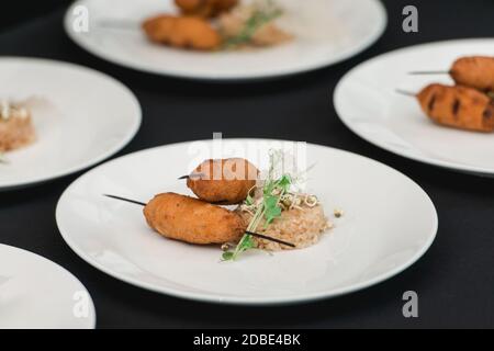 chef che serve succulenti cotolette di carne con un croccante su un piatto in ceramica con riso Foto Stock