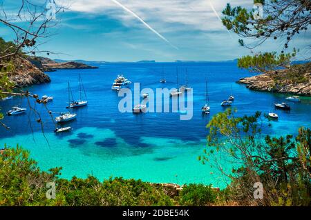 Barche ormeggiate, barche a vela, yacht, motoscafi nella baia di Cala Salada turchese laguna. Idilliaco luogo bellissimo per le vacanze estive, isola di Ibiza. Spagna Foto Stock