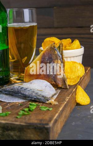 Orata secca in forma di farfalla con birra, limoni e patatine su tavola di legno scuro. Spuntino a base di pesce con birra. Primo piano. Foto Stock