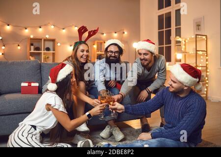 Gruppo di amici che alzano bicchieri di champagne e si augurano a vicenda Buon Natale e felice anno nuovo Foto Stock