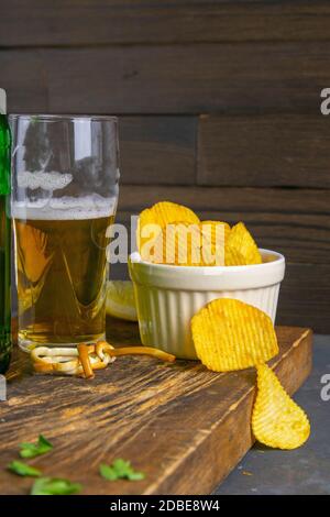 Formaggio con birra, limoni e patatine su tavola di legno scuro. Spuntino a base di pesce con birra. Vista frontale, primo piano. Foto Stock