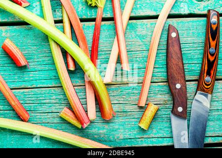 Rhubarb fresco stelo su retro tavola di legno. Pacchetto di steli e pezzi rabarbaro Foto Stock