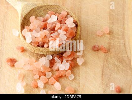 Sale rosa sparso di roccia dell'Himalaya in cucchiaio di legno su sfondo di legno, vista dall'alto. Foto Stock