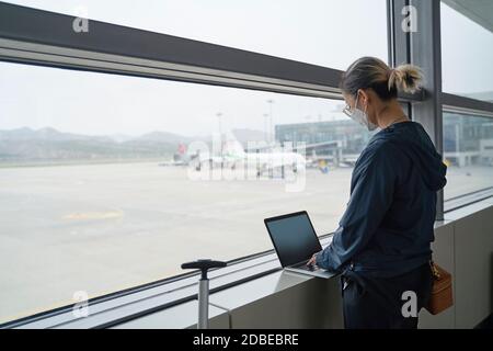 giovane donna asiatica viaggiatore aria femminile che usa il computer portatile durante l'attesa per l'imbarco nell'edificio del terminal dell'aeroporto Foto Stock